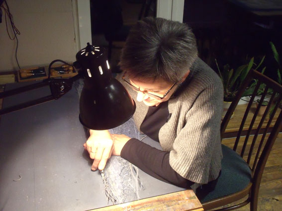 Daliute Ivanauskaite cutting linoleum in her studio